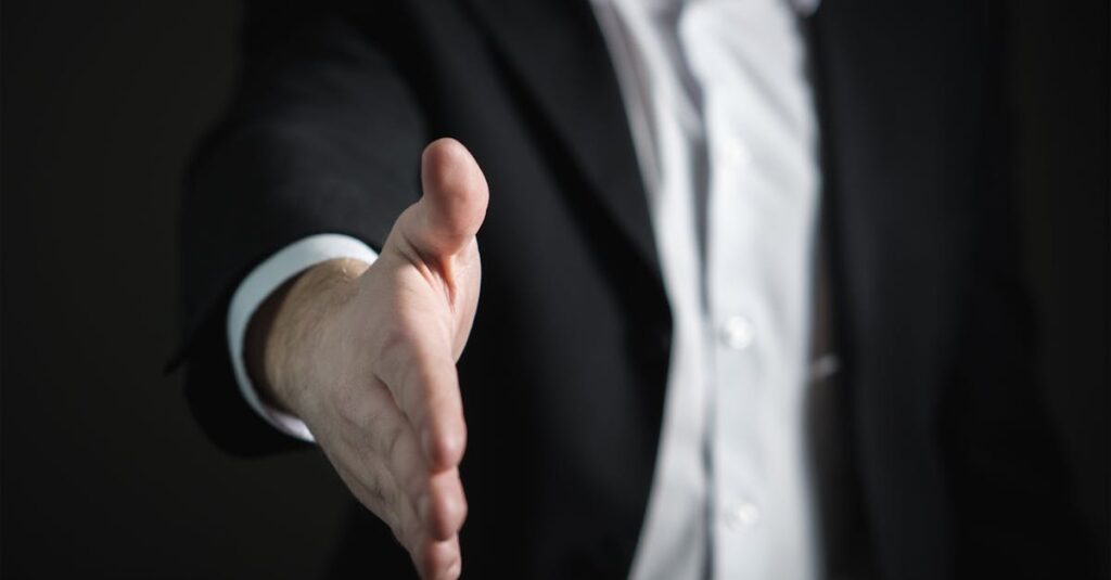 Close-up of a businessman extending hand for a handshake, symbolizing agreement and partnership.