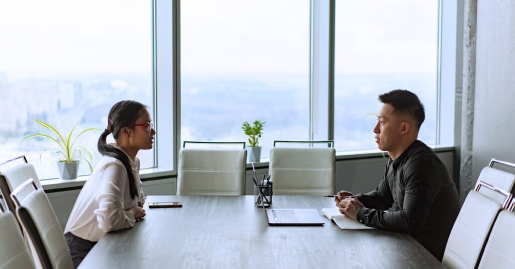Two professionals engaged in a business meeting in a modern office with city views.